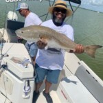 Cast away adventures, man holding a large redfish on a boat during a fishing trip at in Cocoa Beach. Enjoy fun-filled fishing experiences in Florida's beautiful waters. Experience adrenaline and unforgettable memories on the water.